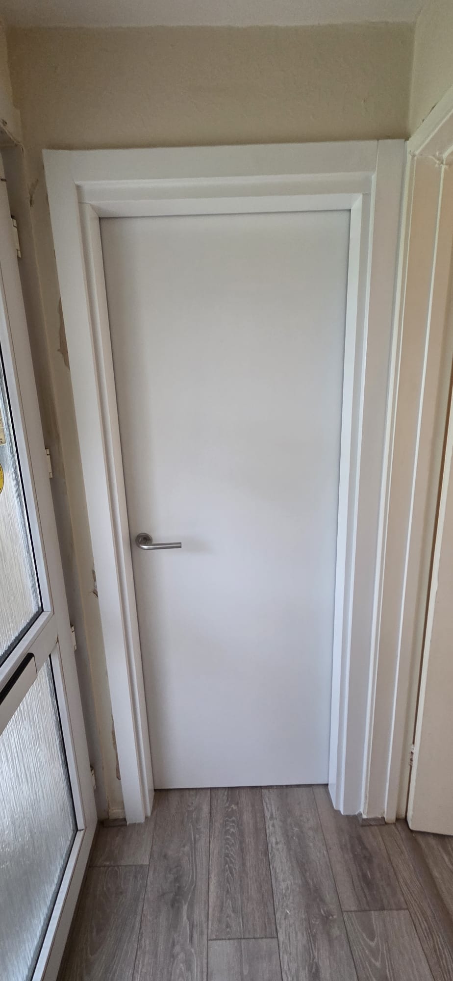 Certified white internal fire door with stainless lever handle installed in a residential hallway
