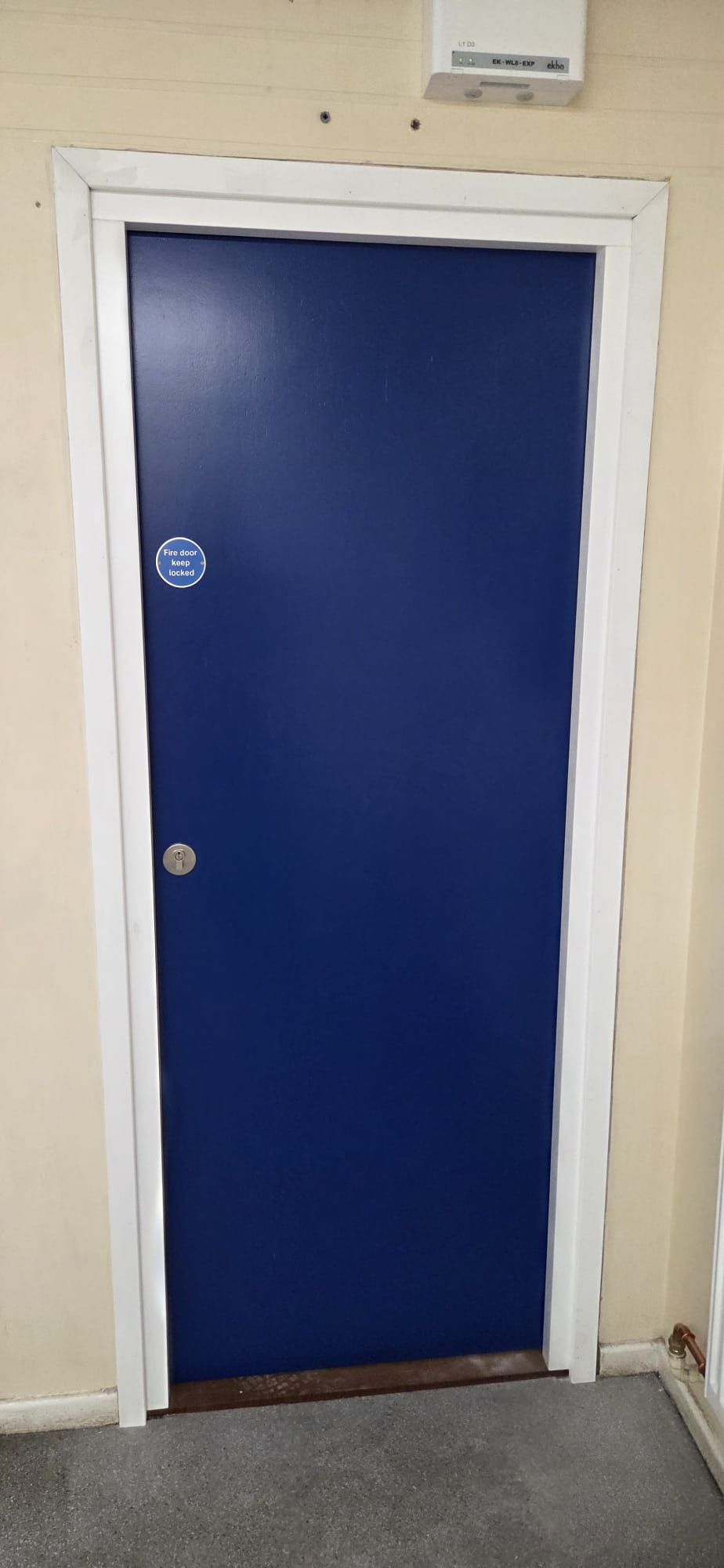 Certified blue solid-core fire door with keep-locked signage installed in a plant room
